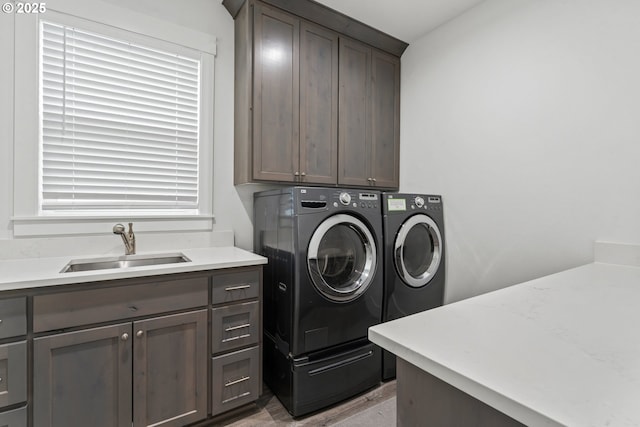 laundry area featuring cabinets, separate washer and dryer, and sink