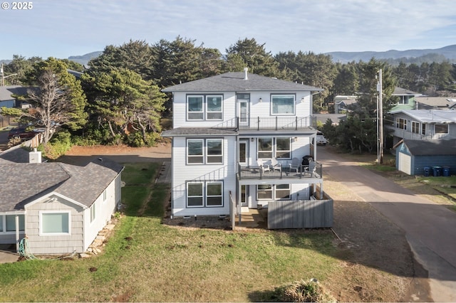 back of property with a balcony and a yard