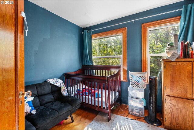 bedroom with hardwood / wood-style flooring and a crib