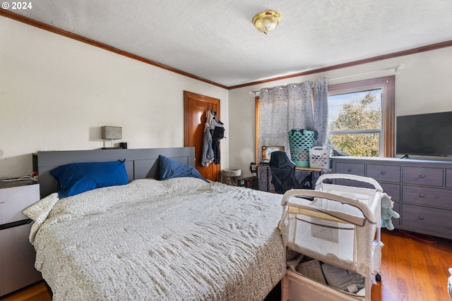 bedroom featuring a textured ceiling, ornamental molding, and wood-type flooring