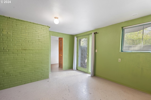 unfurnished room with a healthy amount of sunlight and brick wall