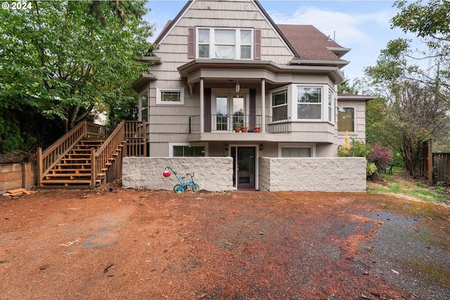 view of front of house with a shingled roof, stairway, fence, and a balcony