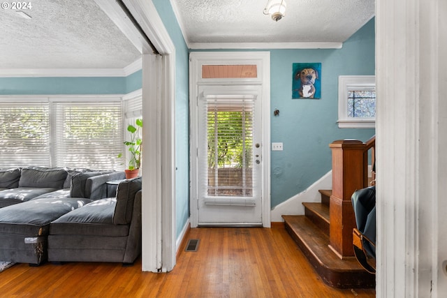 foyer entrance with crown molding, a textured ceiling, and hardwood / wood-style flooring