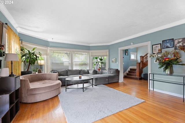 living room featuring baseboards, ornamental molding, wood finished floors, stairs, and a textured ceiling