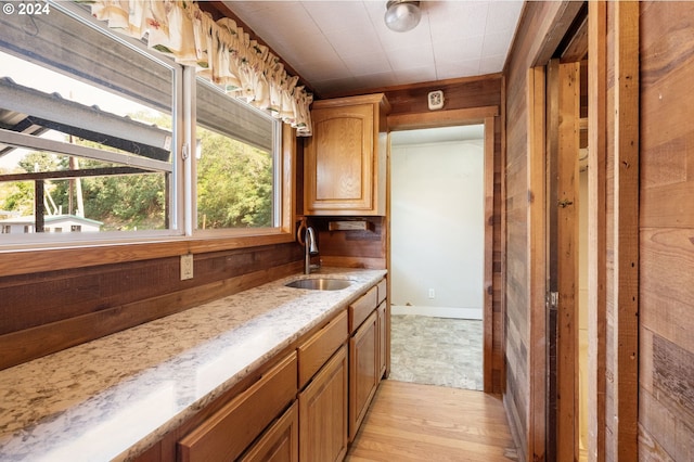 kitchen with wood walls, sink, and light wood-type flooring