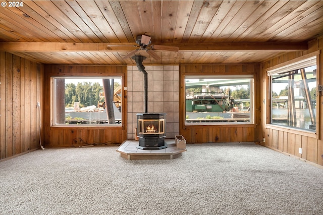 unfurnished living room with wood ceiling, ceiling fan, carpet flooring, and a wood stove