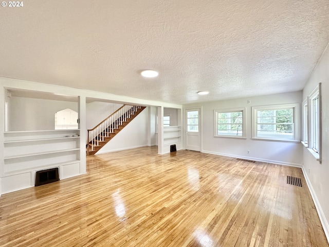 unfurnished living room with wood-type flooring and a textured ceiling