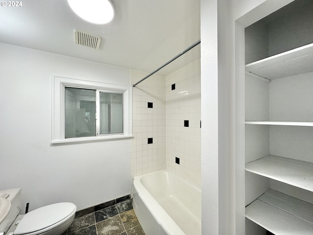 bathroom featuring tiled shower / bath combo and toilet