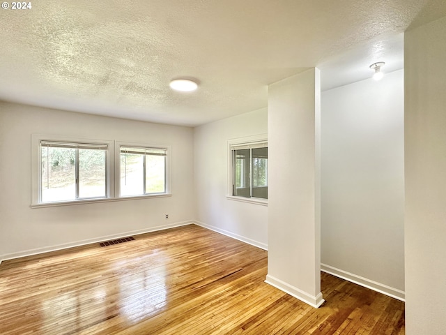 empty room featuring light wood-type flooring and a textured ceiling