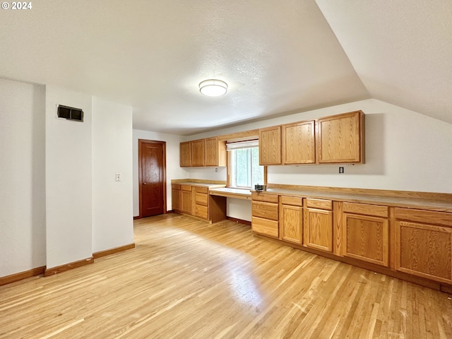 kitchen featuring a textured ceiling, light hardwood / wood-style flooring, and lofted ceiling