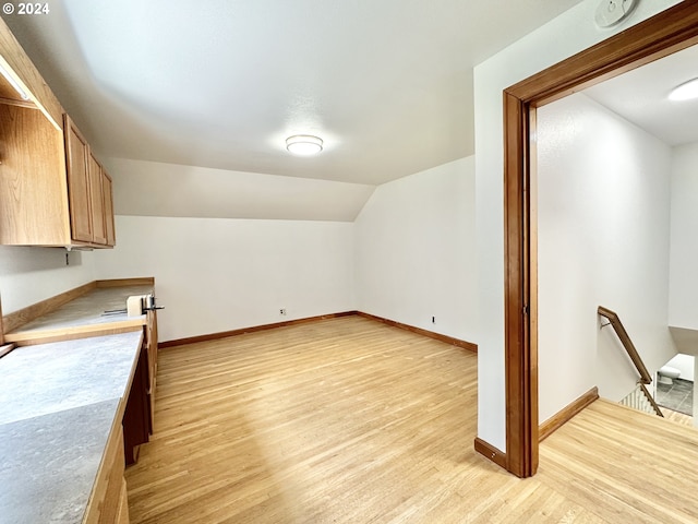 bonus room with light wood-type flooring and vaulted ceiling