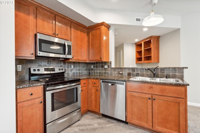 kitchen with appliances with stainless steel finishes, tasteful backsplash, light wood-type flooring, dark stone counters, and sink