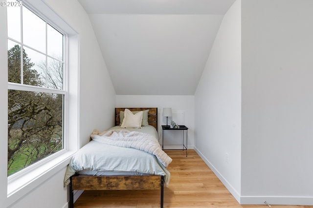 bedroom with hardwood / wood-style floors and lofted ceiling