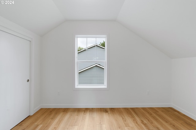 bonus room with light wood-type flooring and vaulted ceiling