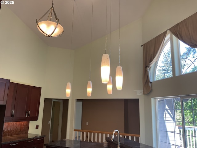 kitchen with a high ceiling, decorative light fixtures, and dark stone countertops