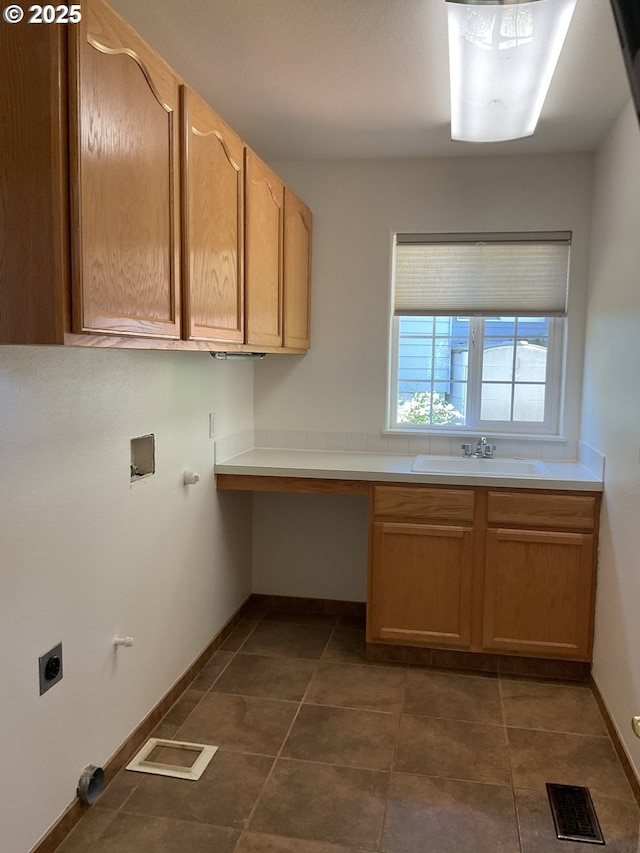 laundry room featuring electric dryer hookup, cabinet space, baseboards, and dark tile patterned floors