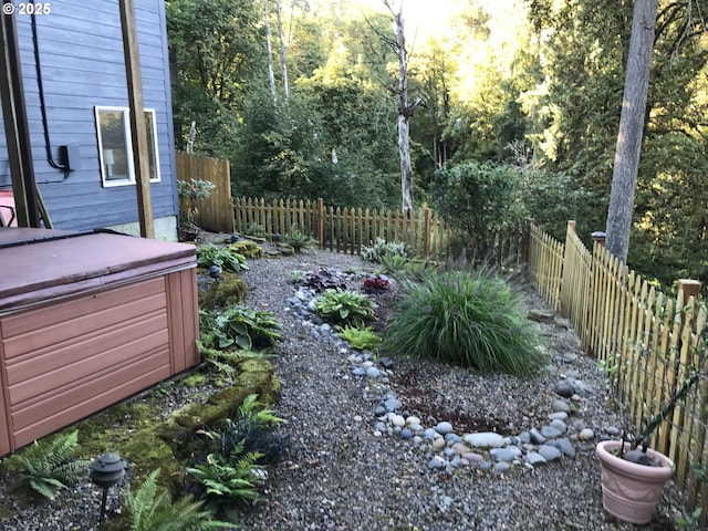 fenced yard featuring a hot tub