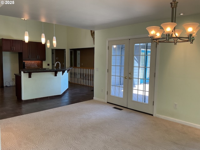 kitchen featuring french doors, a chandelier, dark countertops, a breakfast bar, and baseboards