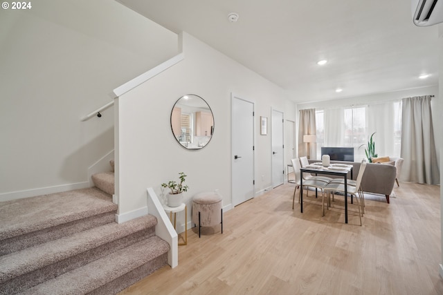 dining space featuring light wood-type flooring and a wall unit AC