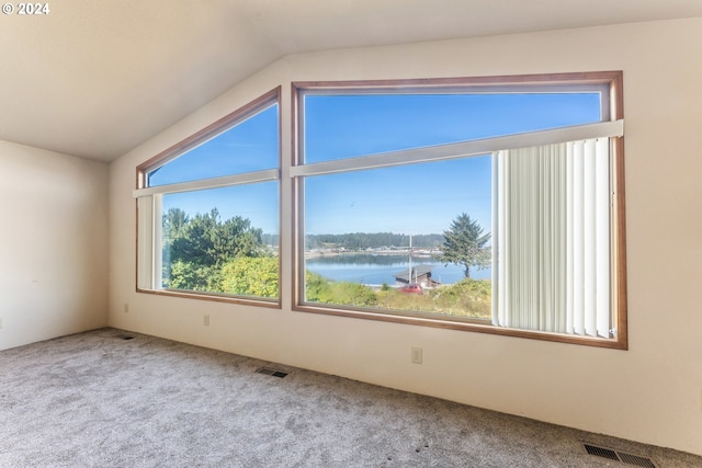 unfurnished room featuring carpet floors, vaulted ceiling, a water view, and a wealth of natural light