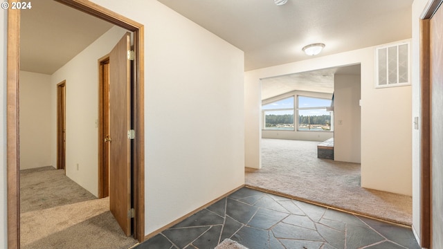 hallway with lofted ceiling and dark colored carpet