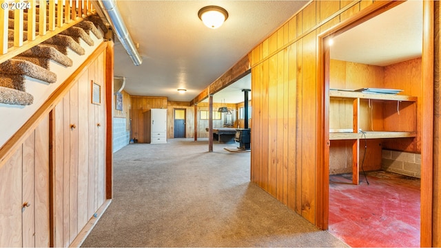 hallway featuring carpet floors, a textured ceiling, and wood walls