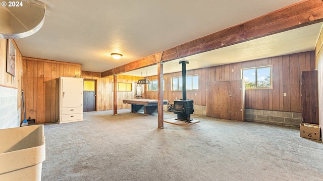 interior space featuring carpet, wood walls, and a wood stove