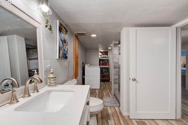 bathroom with vanity, hardwood / wood-style floors, a textured ceiling, and toilet