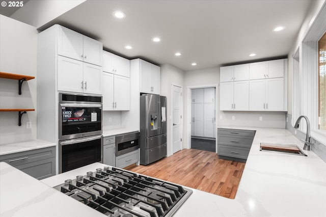 kitchen featuring sink, gray cabinetry, white cabinetry, stainless steel appliances, and light hardwood / wood-style floors