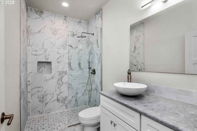 bathroom featuring vanity, a tile shower, and toilet