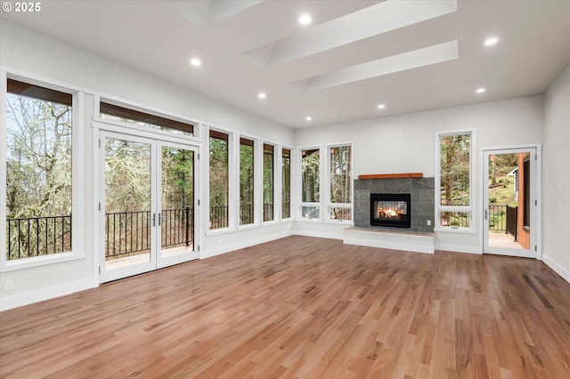 unfurnished living room featuring a tiled fireplace and light hardwood / wood-style flooring