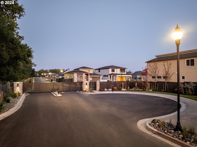 view of street with street lights, a gate, and curbs