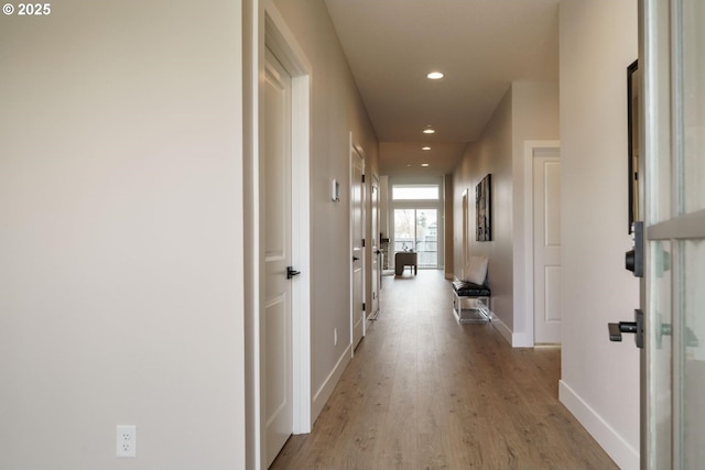 corridor with light wood finished floors, recessed lighting, and baseboards