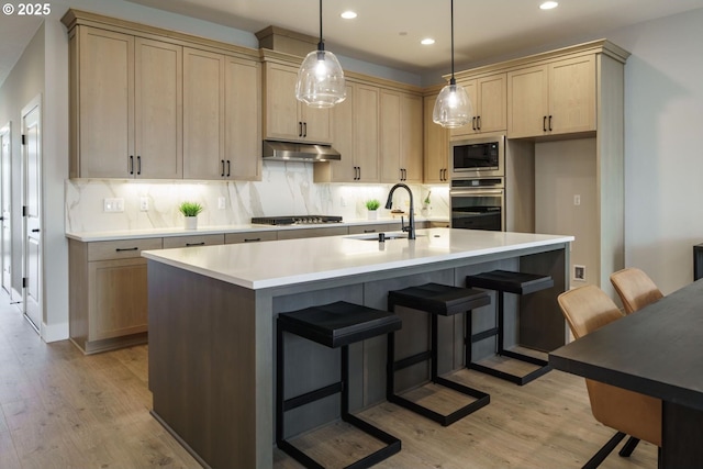 kitchen featuring built in microwave, oven, decorative backsplash, a sink, and under cabinet range hood