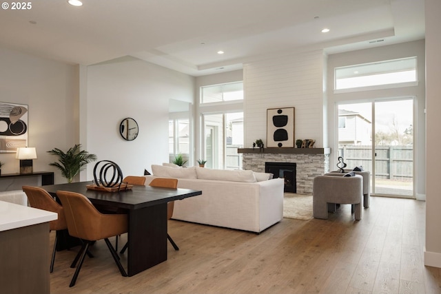 living room with light wood finished floors, recessed lighting, a fireplace, and a high ceiling