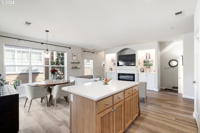 kitchen with decorative light fixtures, a center island, and light hardwood / wood-style flooring