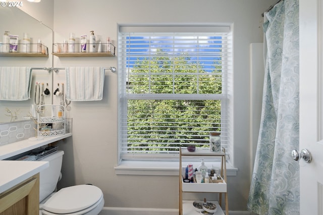 bathroom with a shower with shower curtain, toilet, plenty of natural light, and vanity