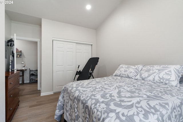 bedroom with lofted ceiling, light hardwood / wood-style flooring, and a closet