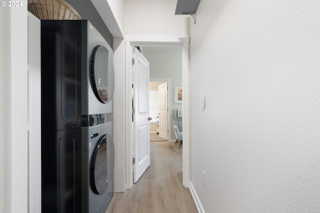 laundry room with light wood-type flooring and stacked washer / drying machine