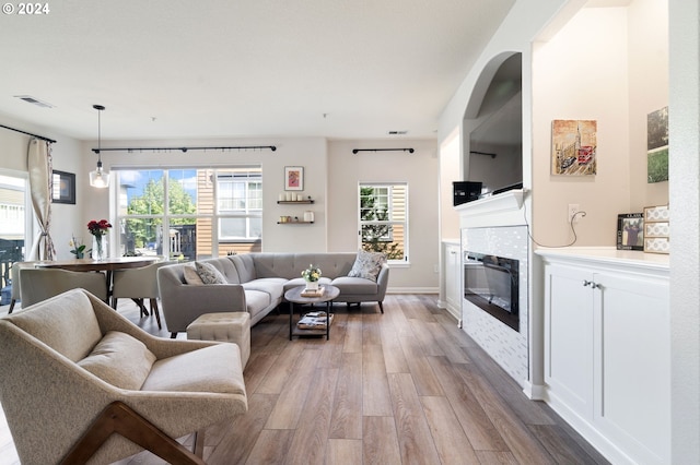 living room featuring light wood-type flooring and a tiled fireplace