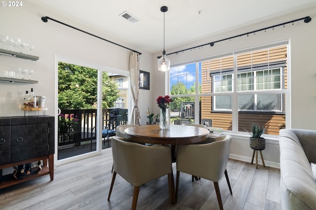 dining space featuring plenty of natural light, indoor bar, and light wood-type flooring