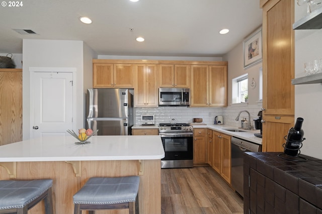 kitchen with a kitchen breakfast bar, stainless steel appliances, wood-type flooring, and sink