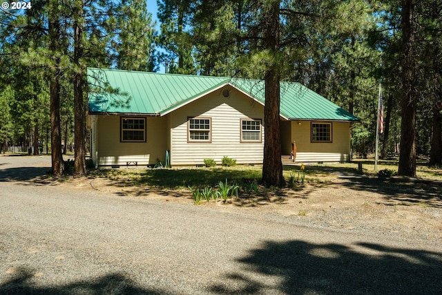 view of front of house with crawl space, dirt driveway, and metal roof