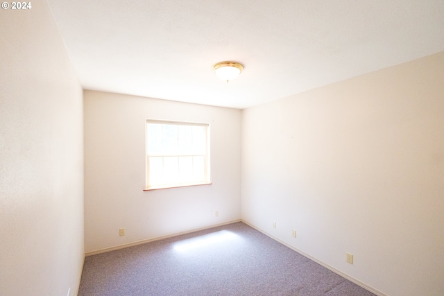 carpeted spare room featuring baseboards