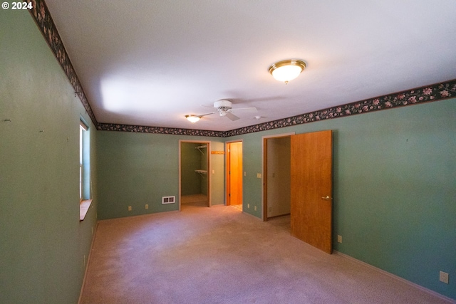 unfurnished bedroom featuring a walk in closet, carpet flooring, and visible vents