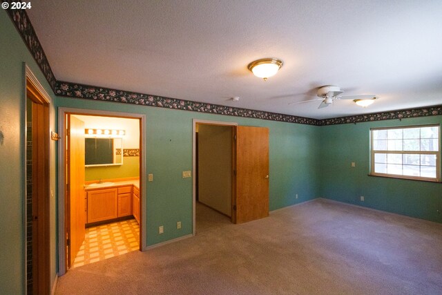 unfurnished bedroom with ensuite bathroom, sink, ceiling fan, and light colored carpet