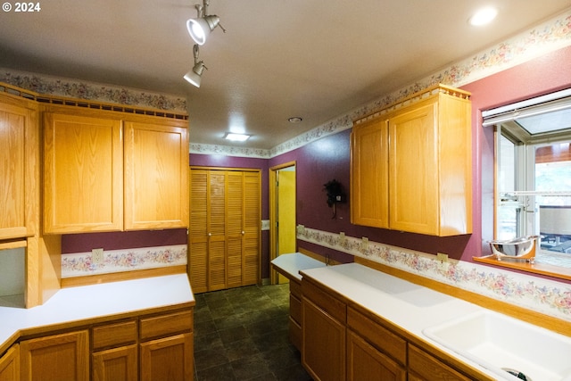 kitchen featuring light countertops, a sink, and wallpapered walls