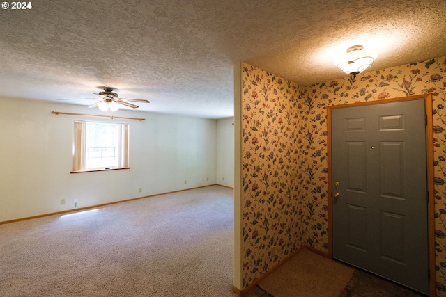 entrance foyer featuring a ceiling fan, dark colored carpet, a textured ceiling, and baseboards