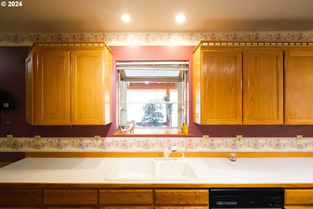 kitchen featuring dishwasher, light countertops, a sink, and brown cabinets