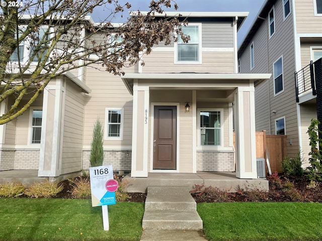 view of front of house with a front lawn, central AC, and brick siding